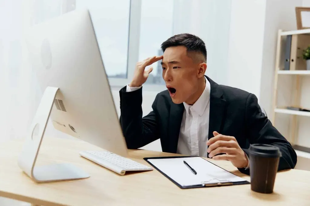 Man staring at computer screen with angry, shocked expression